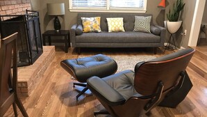 A living room with a gray sofa, two ottomans, a fireplace, a lamp, and a potted plant. - 7 Miles to Masters Tournament - Less Traffic - Sleeps 8 (North Augusta)