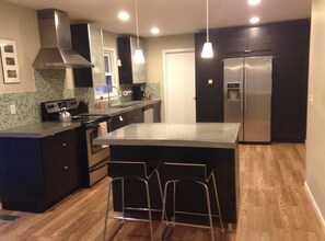 A modern kitchen with a central island, stainless steel appliances, and a tiled backsplash.