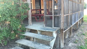 Une cabane en bois rustique, dotée d’une véranda, d’une table et d’un banc.