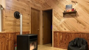 Une pièce chaleureuse avec un poêle à bois, un fauteuil en forme de sac noir et une étagère ornée d’objets décoratifs.
