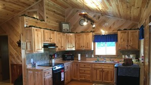 Une cuisine avec des meubles de rangement en bois, un four à micro-ondes, une cuisinière et un réfrigérateur.
