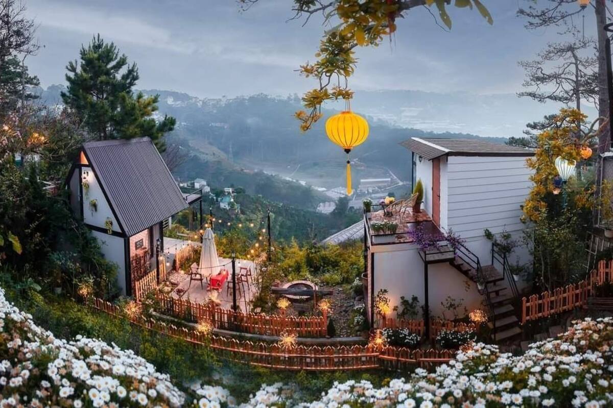 Vista de um monte mostrando uma casa com um pequeno jardim, cerca de madeira e um candeeiro.