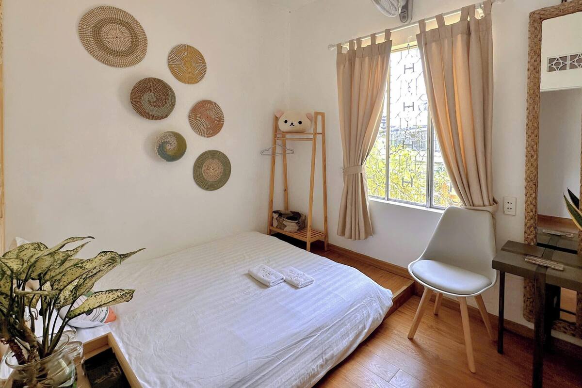 Quarto com cama, cadeira, escrivaninha, espelho e decorações nas paredes.