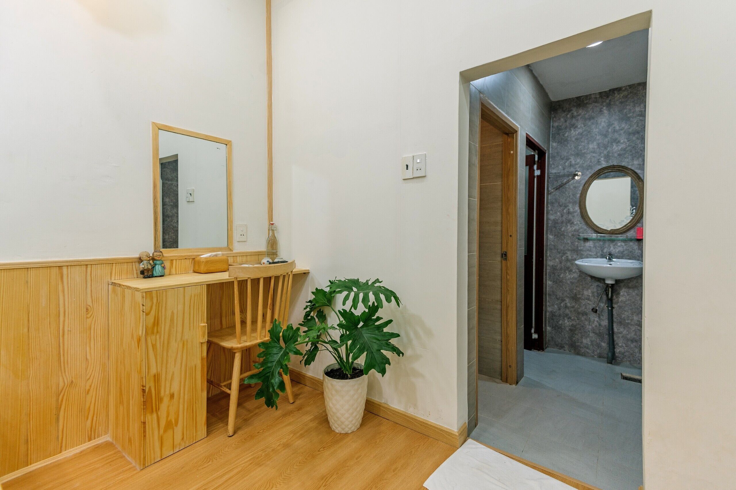 A bathroom with a wooden vanity, a mirror, a sink, and a potted plant.
