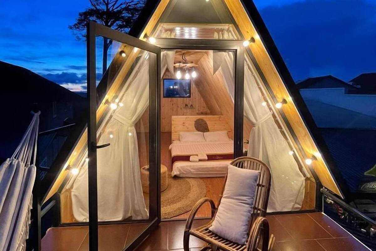 Um quarto em formato de triângulo aconchegante, com cama, TV e poltrona de balanço.