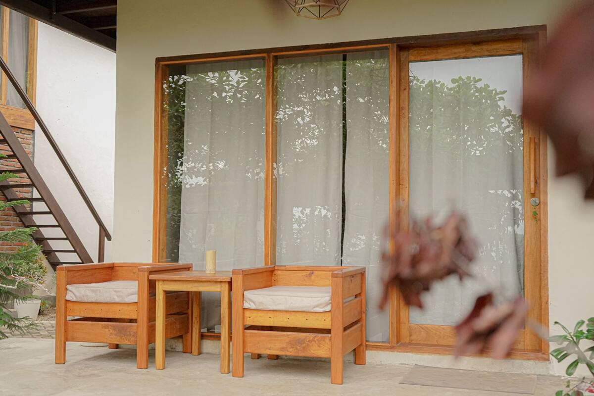 A wooden bench and table set against a sliding glass door with curtains.