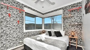 A modern bedroom with a large bed, a window, and a brick-patterned wall. - Luxury Mandalong Mansion with Pool & Spa (Mandalong)