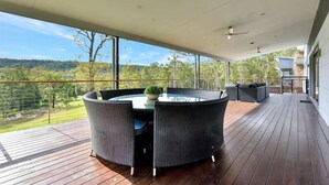 A covered outdoor area with a round table and chairs, a small plant, and a view of a forested landscape. - Luxury Mandalong Mansion with Pool & Spa (Mandalong)