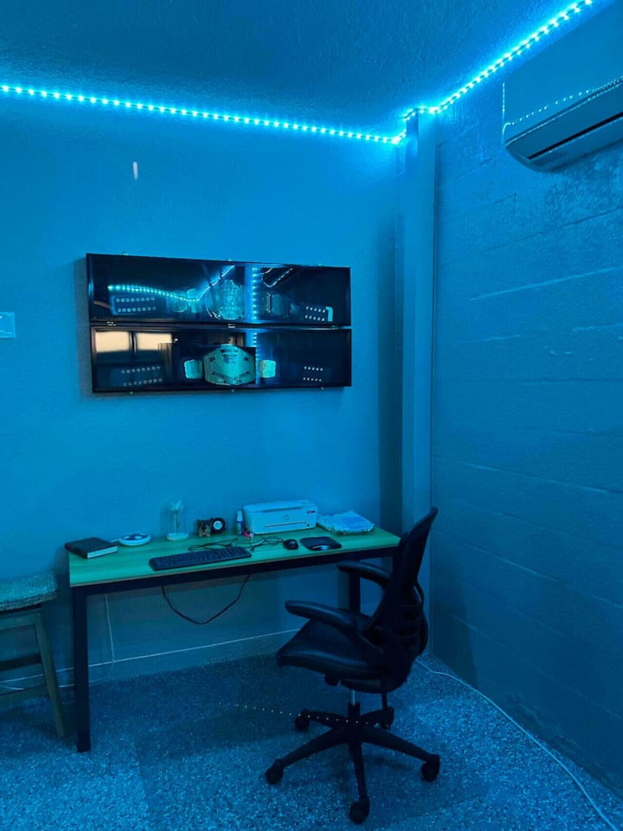 A room with a desk, chair, and a wall-mounted display unit.