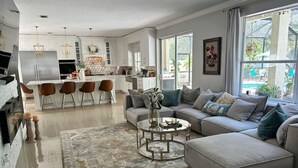 A modern kitchen with white cabinets, stainless steel appliances, and a dining area with brown chairs.