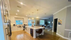 A spacious kitchen with a large island, white cabinetry, and pendant lighting.