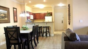 Comedor con mesa y sillas, cocina al fondo y sala de estar con sofá.