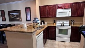 Una cocina con una isla central, electrodomésticos blancos y armarios de madera oscura.