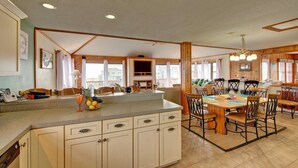 A spacious kitchen with a central island, wooden cabinets, and a dining area with a large table and chairs. - Semi-Oceanfront, Beach Access, Hot Tub & Pool Table (Avon)