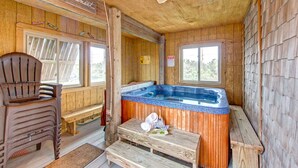 A wooden cabin with a hot tub, wooden furniture, and a sign reading "Majestic Sunset". - Semi-Oceanfront, Beach Access, Hot Tub & Pool Table (Avon)