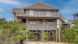 A two-story house with a balcony on the upper floor, wooden railings, and a staircase leading to the upper level. - Semi-Oceanfront, Beach Access, Hot Tub & Pool Table (Avon)