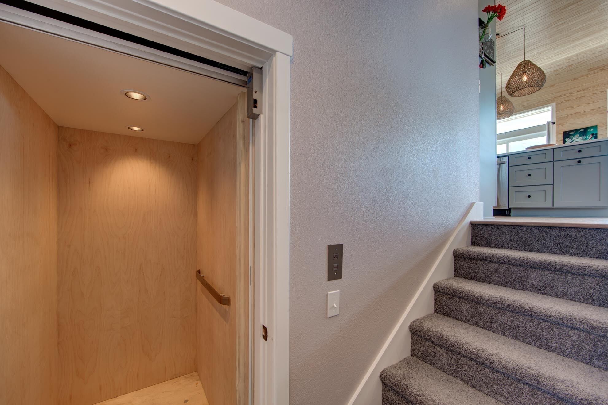 A staircase with carpeted steps leading to a kitchen area.