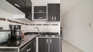 A modern kitchen with dark cabinetry, a stainless steel sink, and a black countertop.