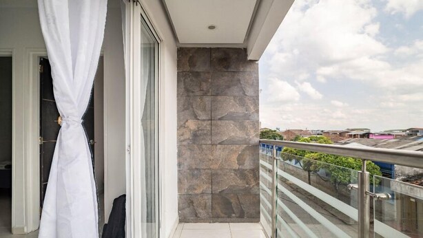 A balcony with a stone wall, a glass railing, and a view of the cityscape.
