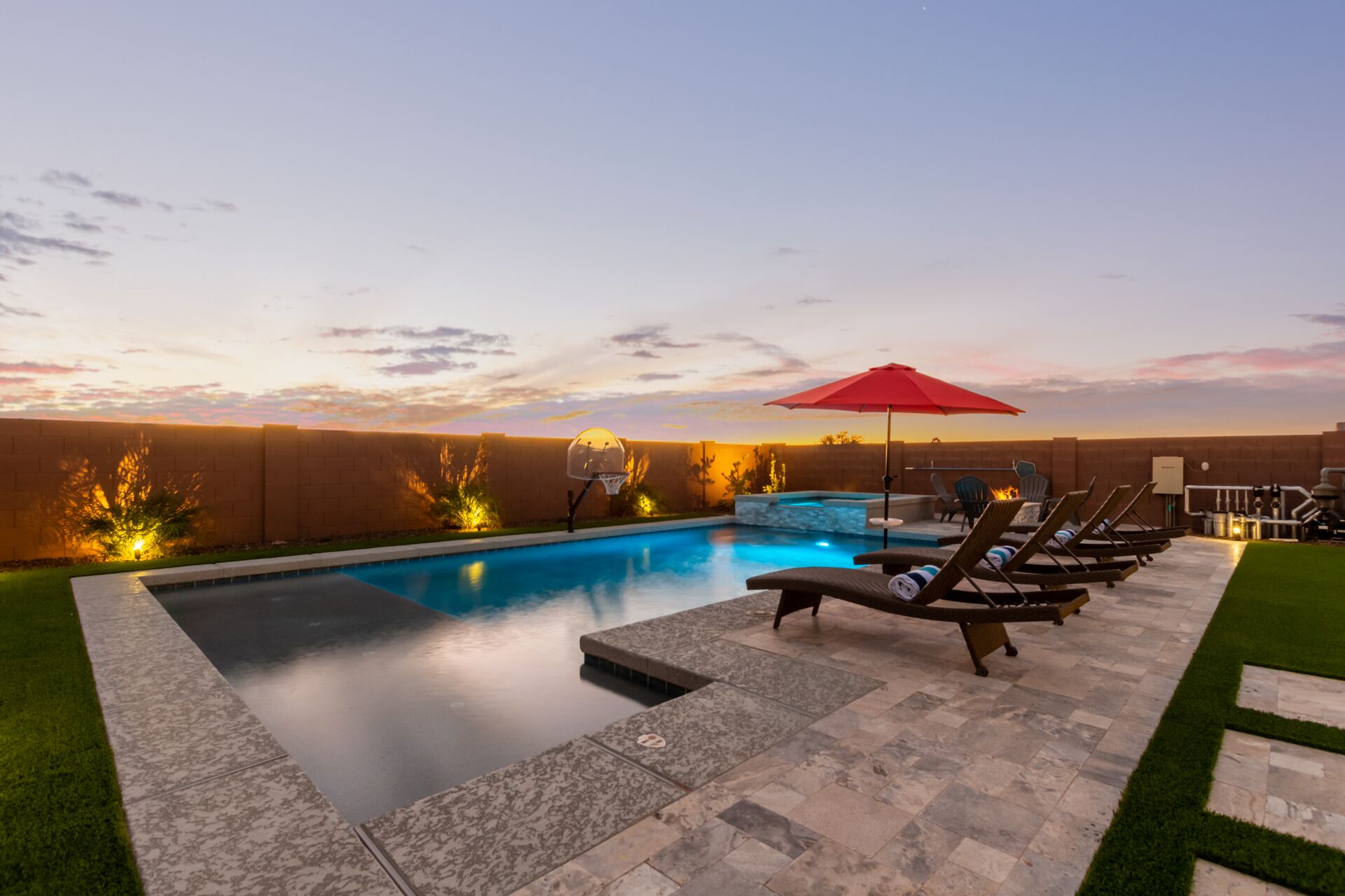 A swimming pool with a sunken seating area, surrounded by a brick wall and a grassy lawn.