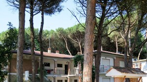 A two-story house with a balcony, surrounded by trees.