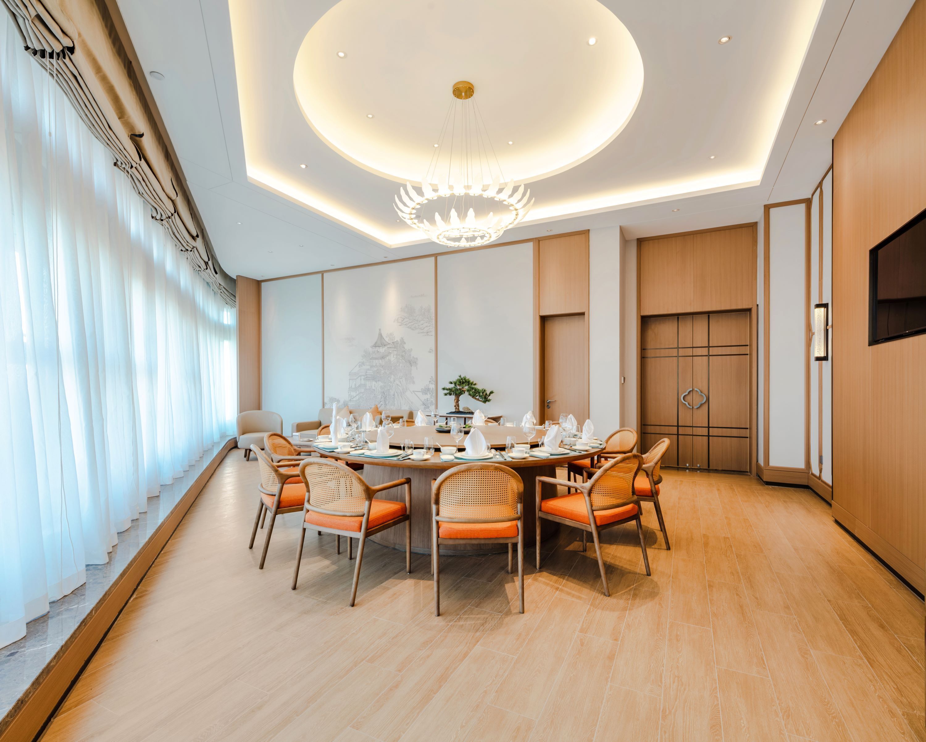 A modern dining room with a round table set for six, surrounded by wicker chairs.