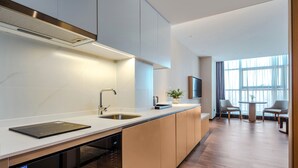 A modern kitchen with a built-in dishwasher, a sink, and a dining area with a table and chairs. - Shanxi Xiaohe Xincheng Talent Apartment (Taiyuan)