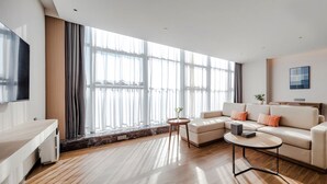 A modern living room with a sectional sofa, a coffee table, and a TV mounted on the wall. - Shanxi Xiaohe Xincheng Talent Apartment (Taiyuan)