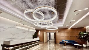 A modern lobby with a marble reception desk, a blue seating area, and a unique ceiling design. - Shanxi Xiaohe Xincheng Talent Apartment (Taiyuan)