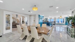A spacious dining area with a marble floor, a wooden table, and white chairs. - Bay-Front Dream Mansion and Guest House -20 minutes to Destin beaches on 4 acres (Freeport)