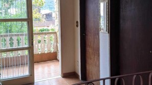Una habitación con un ventanal grande, una puerta de madera oscura y un suelo de baldosas.