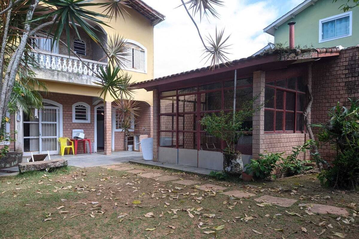 A two-story building with a covered patio area, a brick facade, and a small garden with palm trees.