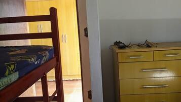 Una habitación con una cama litera, un aparador de madera y una puerta que da a otra estancia.
