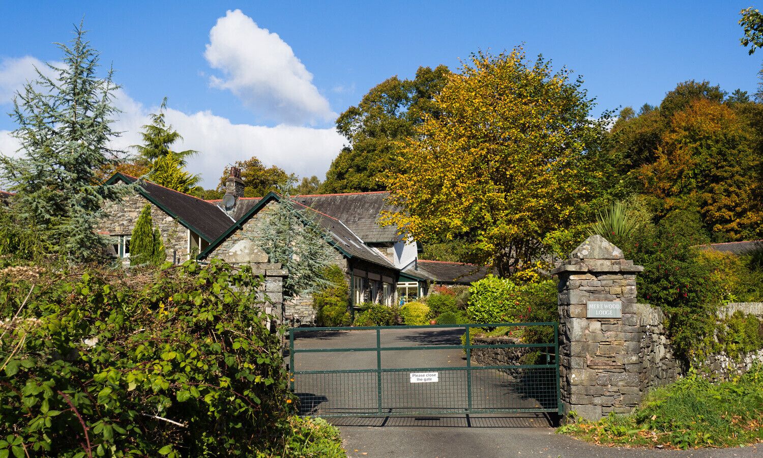 A stone-built lodge with a traditional design, surrounded by lush greenery and trees.