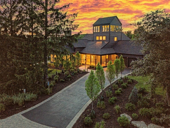 A large, multi-story house with a well-maintained garden and a paved driveway.