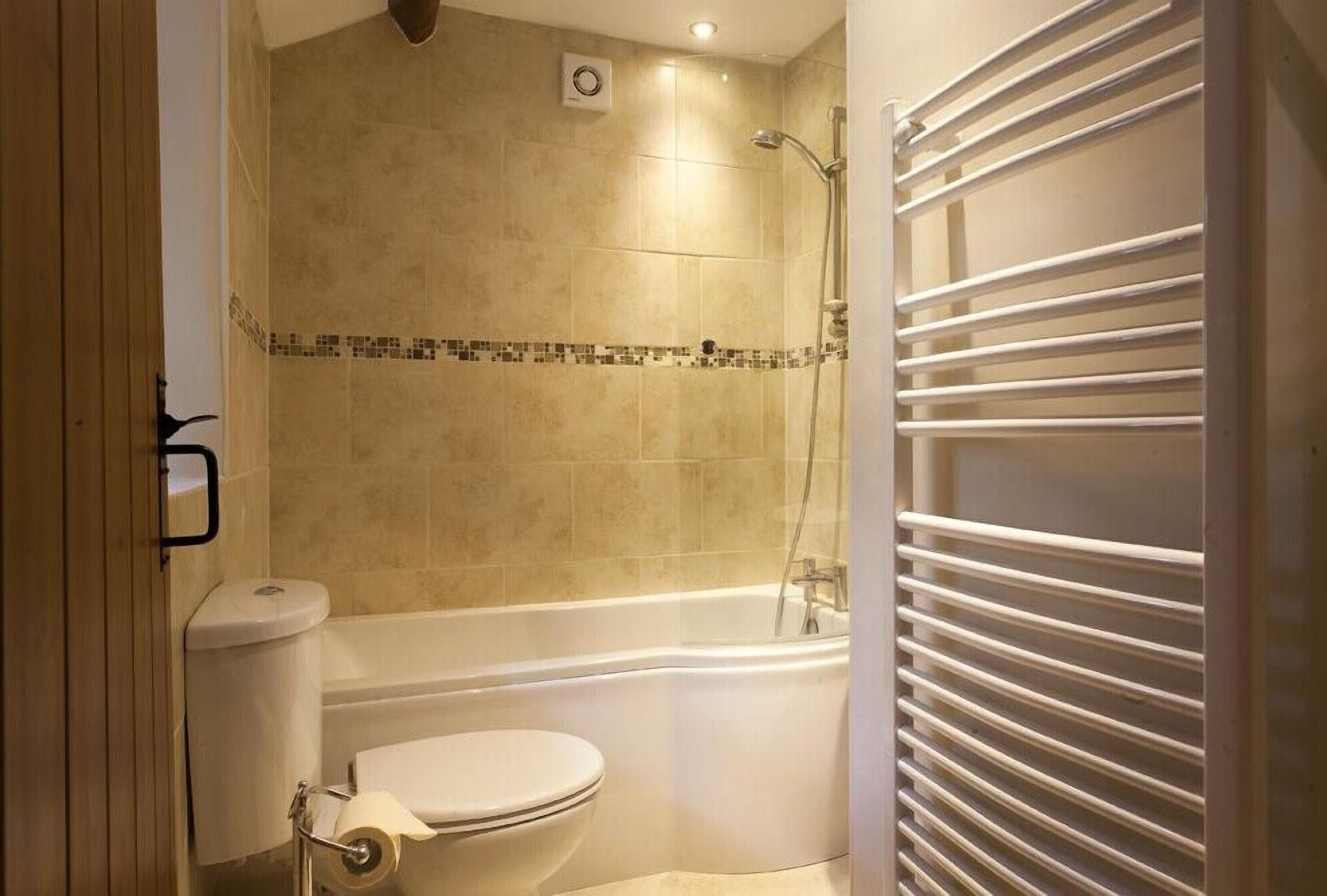 A bathroom with a toilet, bathtub, and shower.