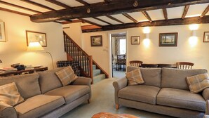 A cozy living room with two sofas, a wooden coffee table, and a staircase leading to another room. - Ecclerigg Old Farm (Windermere)