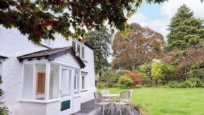 A white house with a patio, a table and chairs, and a garden. - Ecclerigg Old Farm (Windermere)