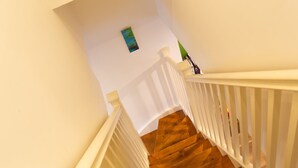 Un escalier en bois avec des rampes blanches et un petit tableau accroché au mur.