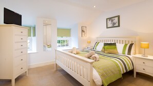 Une chambre à coucher comprenant un lit, des tables de chevet, une armoire, un miroir et une fenêtre.