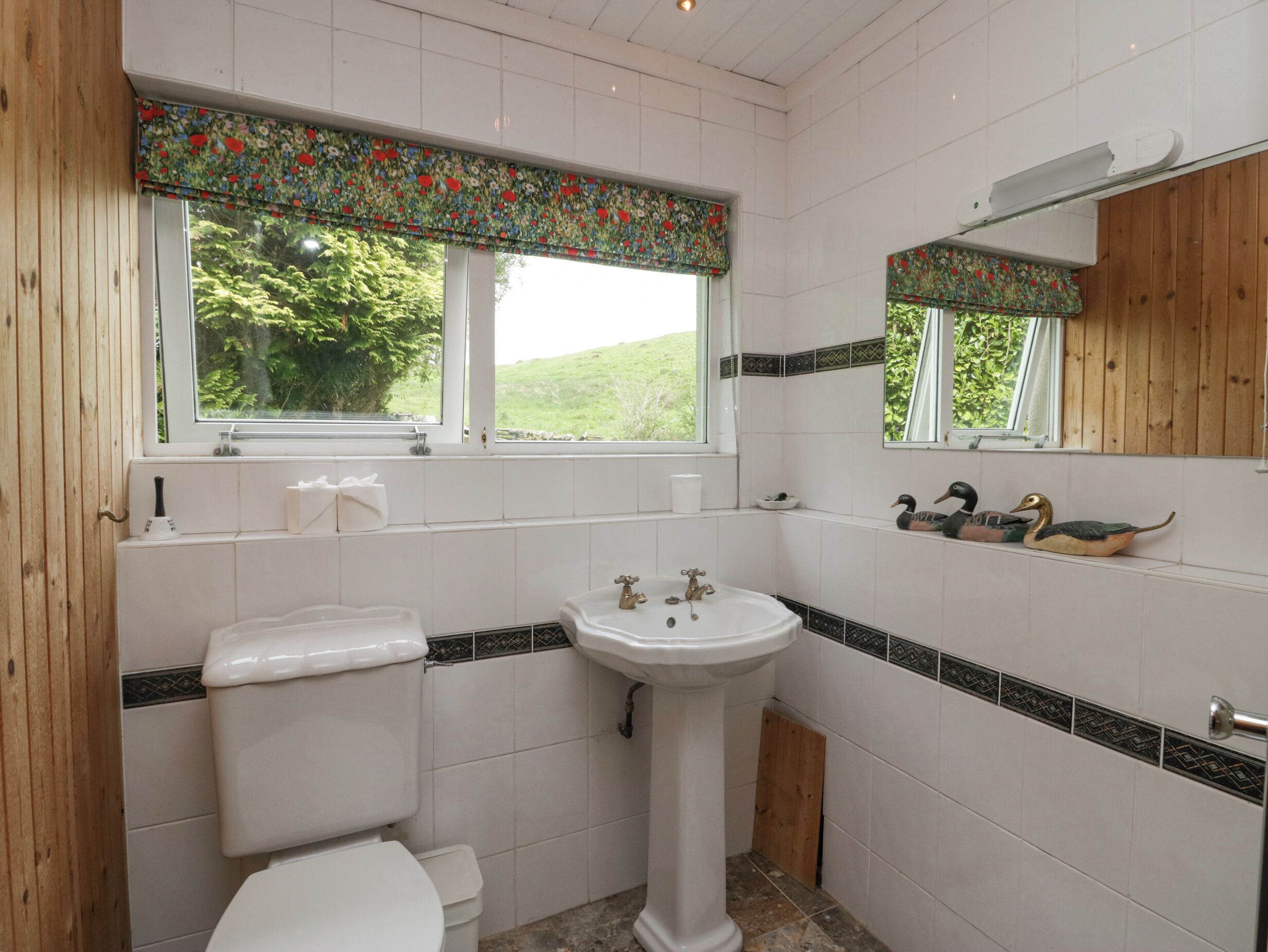 A bathroom with a toilet, sink, and window.