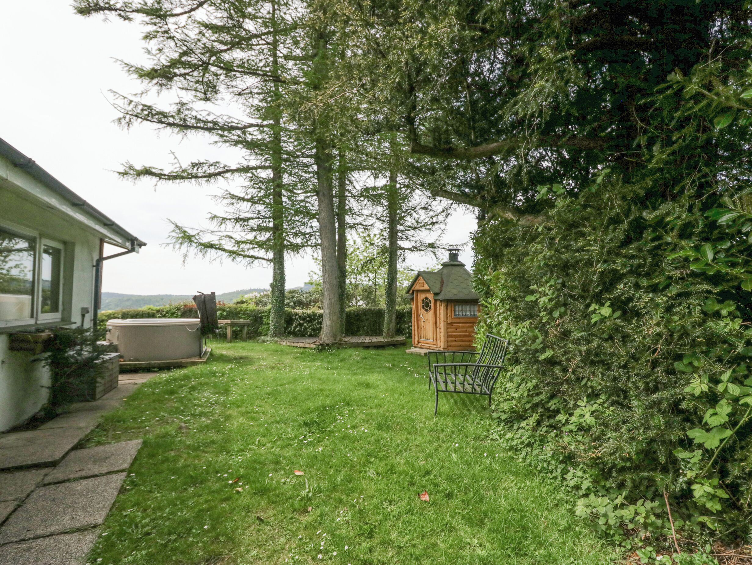 A backyard with a wooden playhouse, a hot tub, and a lawn.