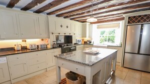 A modern kitchen with white cabinets, a granite countertop island, and a stainless steel refrigerator. - Low Cartmell Fold (Kendal)