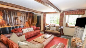 A cozy living room with a leather sofa, a red plaid sofa, and a wooden coffee table. - Low Cartmell Fold (Kendal)