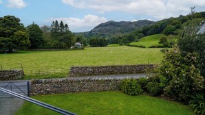 A rural landscape with a stone wall, a grassy field, and a stone building. - The Old Police House (Ambleside)