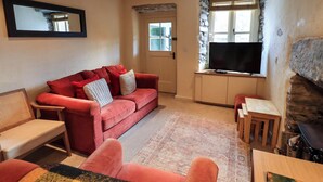 Ein Wohnzimmer mit einem roten Sofa, einem Fernseher und einem Kamin aus Stein.