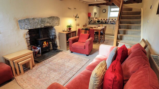 Ein gemütliches Wohnzimmer mit Kamin, einem roten Sofa und einer Treppe, die zur Küche führt.