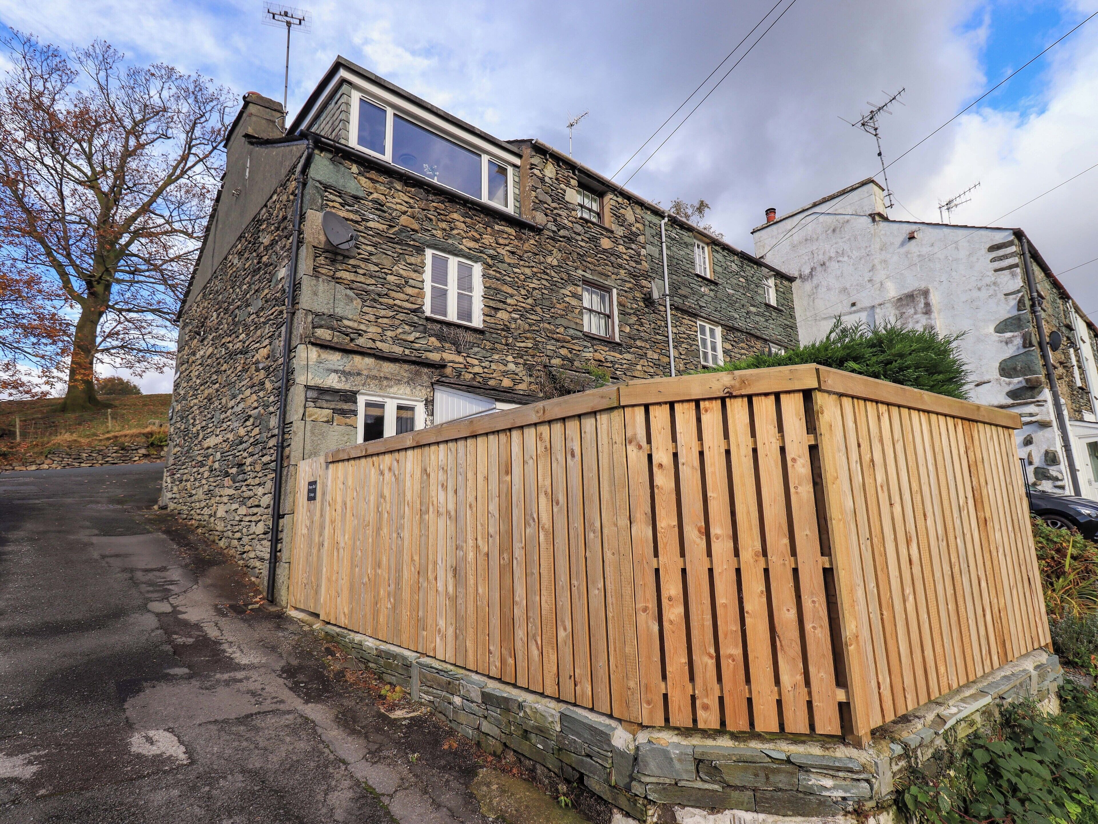 A stone house with a wooden fence, a satellite dish, and a clear sky.