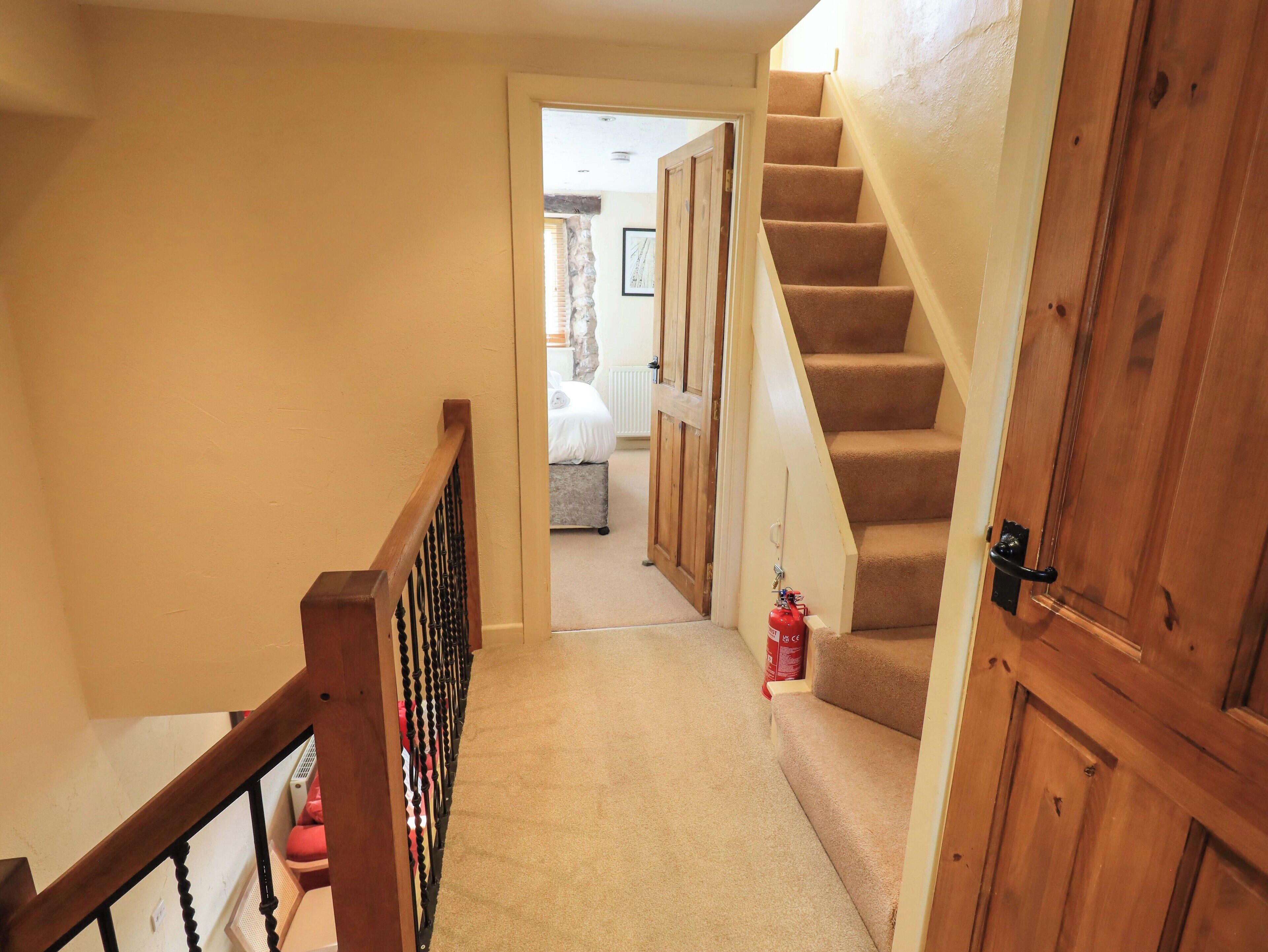 A carpeted hallway with wooden doors and a staircase.
