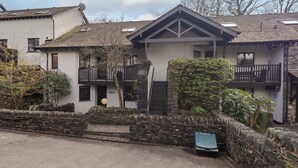 A two-story building with a stone facade, a balcony, and a small garden area. - Gillybeck (Ambleside)